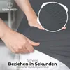 A close-up of hands stretching a dark gray fabric, likely a bedsheet, with a magnified inset showing the elasticized edge. Produktbild-Vorschau