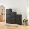 A collection of black shoe cabinets arranged in a stepped formation against a white wall, with a rug in front and a plant to the side. Produktbild-Vorschau