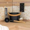 Sauna accessories including a bucket, ladle, thermometer, and hourglass are arranged on wooden benches in a sauna. Náhled obrázku produktu