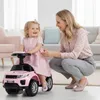 A mother is watching her daughter play with a pink ride-on car indoors. Produktbild-Vorschau
