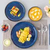 A table setting with plates of food, a bowl of soup, and cutlery. Produktbild-Vorschau