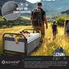 A family is walking through a grassy field with a wagon full of picnic items. Produktbild-Vorschau