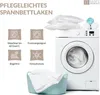 A washing machine with pillows and towels on top, and icons detailing product features. Produktbild-Vorschau