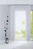 A sheer white curtain hangs in front of a window, with a decorative branch in a vase and a lantern on the floor in the foreground. Produktbild-Vorschau