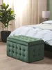 A green tufted storage ottoman is placed in front of a bed in a bedroom. Produktbild-Vorschau