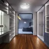 A modern walk-in closet with built-in shelving and lighting, leading to a bedroom. Produktbild-Vorschau