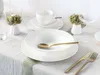 A table setting with white porcelain dishes, gold cutlery, and small floral arrangements. Náhľad obrázku produktu