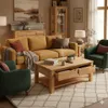 A living room scene featuring a yellow couch, green armchair, and a wooden coffee table. Produktbild-Vorschau