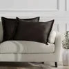 Two dark brown velvet throw pillows are placed on a light-colored sofa. Produktbild-Vorschau