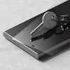 A close-up shot of a smartphone screen protector being applied to a smartphone, with a key resting on top. Produktbild-Vorschau