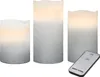 Three LED candles of varying heights are arranged on a white background, with a remote control in the foreground. Produktbild-Vorschau