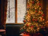 A decorated Christmas tree is in the foreground, with a snowy forest scene visible through a window in the background. Produktbild-Vorschau