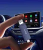 A hand holding a Carlinkit adapter in front of a car's infotainment screen. Produktbild-Vorschau