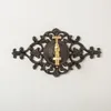 A decorative cast iron faucet with a brass handle mounted on a textured white wall. Voir les images du produit