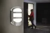 A person is opening a door at night, illuminated by an outdoor wall light. Podgląd zdjęcia produktu