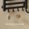 A close-up view of a black towel warmer with hooks holding a bath brush and a loofah. Text overlays provide marketing information. Anteprima dell’immagine prodotto