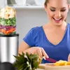 A woman is preparing ingredients for a smoothie next to a blender. Produktbild-Vorschau