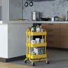 A yellow kitchen cart filled with various items is placed in a modern kitchen setting. Voir les images du produit