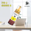 A bottle of yellow ink refill is shown in front of a laptop on a desk. Náhled obrázku produktu
