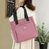 Rosa Stofftasche mit schwarzen Riemen, über der Schulter einer Person in weißer Jacke getragen Náhľad obrázku produktu
