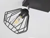 A close-up shot of a black metal wire cage ceiling light fixture with an Edison-style LED bulb. Produktbild-Vorschau