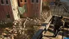 A person runs across a wooden bridge towards a large group of zombies gathered around a red barn. Produktbild-Vorschau