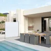 An outdoor patio setting with a dining table and chairs, a swimming pool, and a white privacy screen. Produktbild-Vorschau