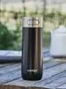 A black Contigo thermobecher sits on a wooden table outdoors, with a white teapot in the background. Anteprima dell’immagine prodotto