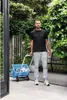 A man is pulling a shopping cart with a blue basket in a garden. Náhled obrázku produktu