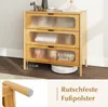A wooden cabinet with three ribbed glass drawers is shown in a room setting. A robot vacuum cleaner is underneath the cabinet. A close-up of a leg with a protective pad is shown in a separate inset. Podgląd zdjęcia produktu