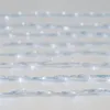 A close-up, slightly blurred view of multiple strands of white LED string lights laid out horizontally against a light background. Voir les images du produit
