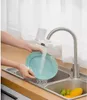 A person is washing a teal plate under a faucet with a water filter attached. Náhľad obrázku produktu