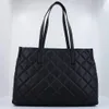 A black quilted tote bag with two shoulder straps, presented against a white background. Produktbild-Vorschau