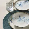 A close-up view of plates and a glass on a placemat. Produktbild-Vorschau