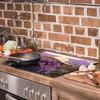 A glass stovetop protector with a lavender field and hat design is placed on a kitchen counter next to a stove. Náhled obrázku produktu