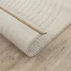 A close-up view of a rolled-up rug on a wooden floor. Produktbild-Vorschau
