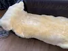 A sheepskin rug is laid out on a dark brown leather sofa. Produktbild-Vorschau
