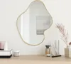 A decorative mirror with a gold frame is displayed on a wall above a wooden vanity table, which holds various cosmetic items and a dried floral arrangement. Podgląd zdjęcia produktu
