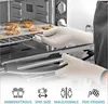 A person wearing oven mitts is taking a tray of cookies out of an oven. Produktbild-Vorschau
