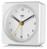 A white Braun analog alarm clock with black hands and a yellow second hand, shown from a slight angle. Podgląd zdjęcia produktu