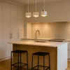 A modern kitchen with a central island, featuring pendant lights and bar stools. Produktbild-Vorschau