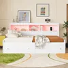 A white bed with storage drawers and a lighted headboard with shelves, decorated with artwork and a clock. Náhled obrázku produktu