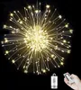 A starburst-shaped light decoration with many small lights emanating from a central point, shown against a black background. A remote control and a battery pack are visible in the lower right corner. Produktbild-Vorschau
