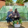 A couple posing in front of a greenhouse with a basket of harvested vegetables. Produktbild-Vorschau
