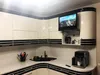 A modern kitchen with white and black cabinets, a sink, a coffee machine, and a small TV mounted above the cabinets. Produktbild-Vorschau