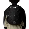 A person wearing a black jacket and a beige jacket underneath, with a black backpack on their back. Produktbild-Vorschau