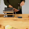 A person is assembling a pasta maker on a wooden table. Anteprima dell’immagine prodotto