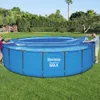 Two people are putting a solar cover on a round, blue swimming pool in a grassy backyard. Náhled obrázku produktu