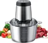 A stainless steel food chopper with a clear plastic lid, surrounded by fresh ingredients like vegetables and raw meat. Produktbild-Vorschau