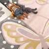 A close-up view of a children's rug with butterfly and polka dot patterns, featuring two stuffed toys. Voir les images du produit